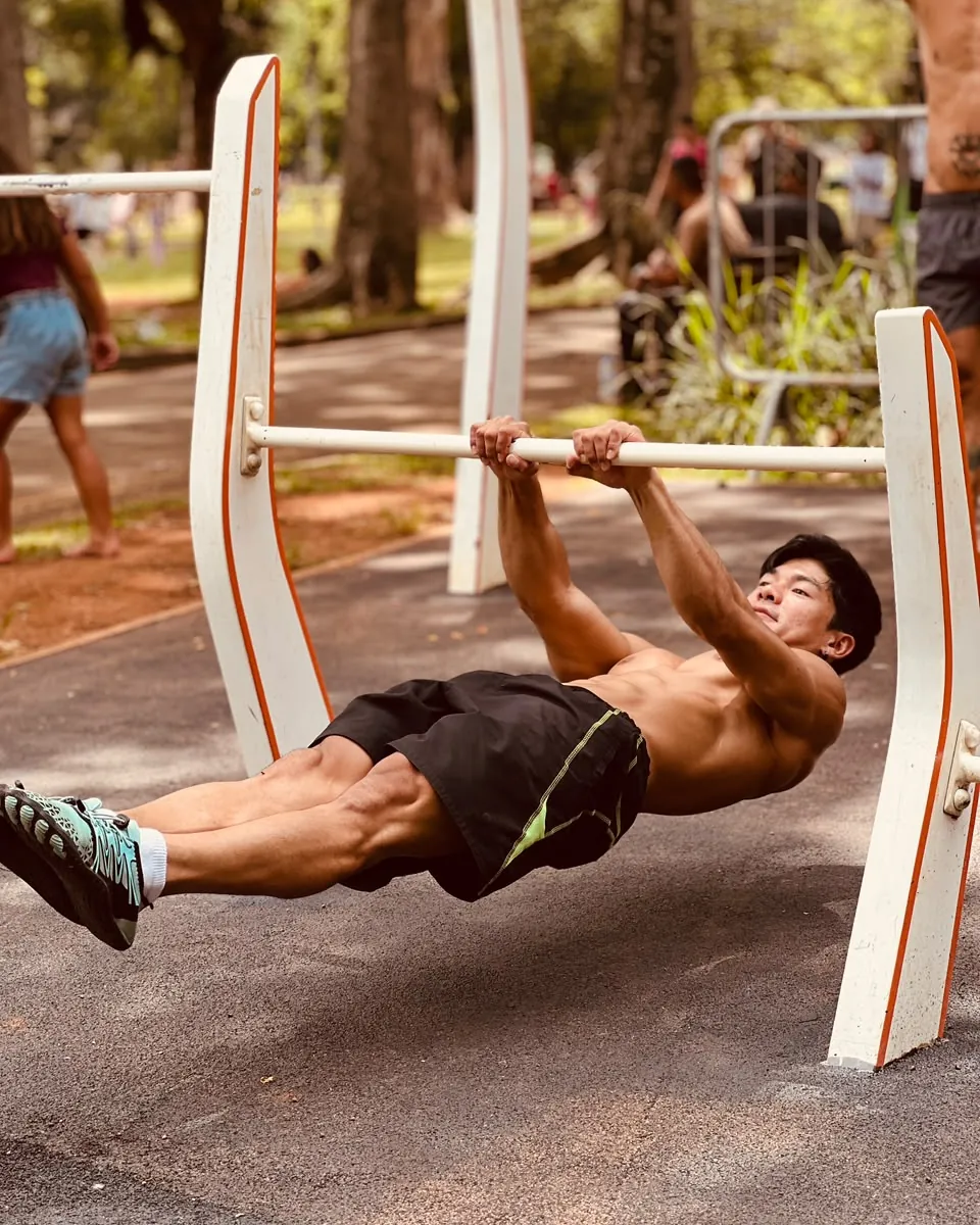 Vinicius Tsuha executando um front lever numa barra de parque.